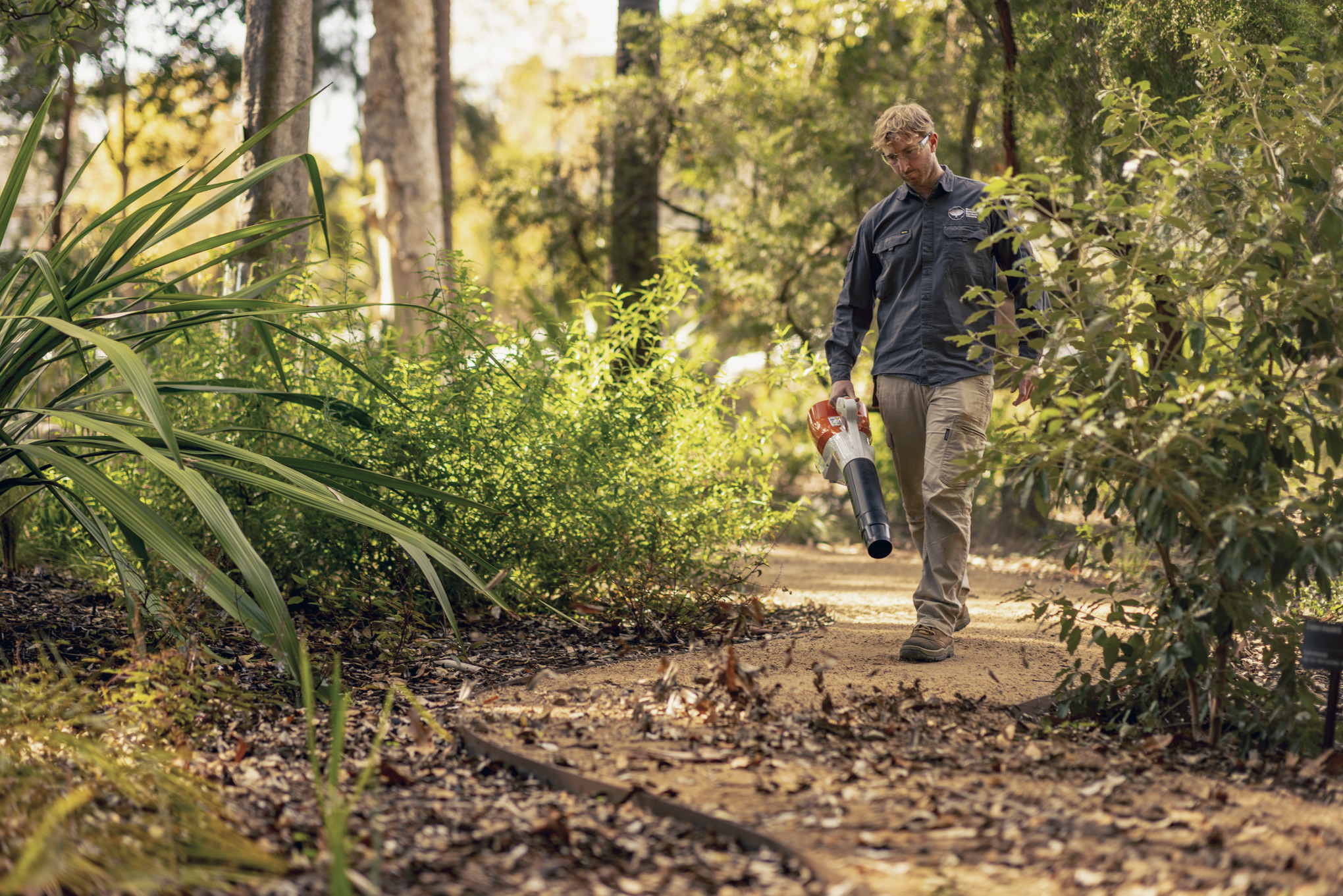 Nahaufnahme: Mann, der mit dem STIHL Laubbläser Laub zur Seite bläst