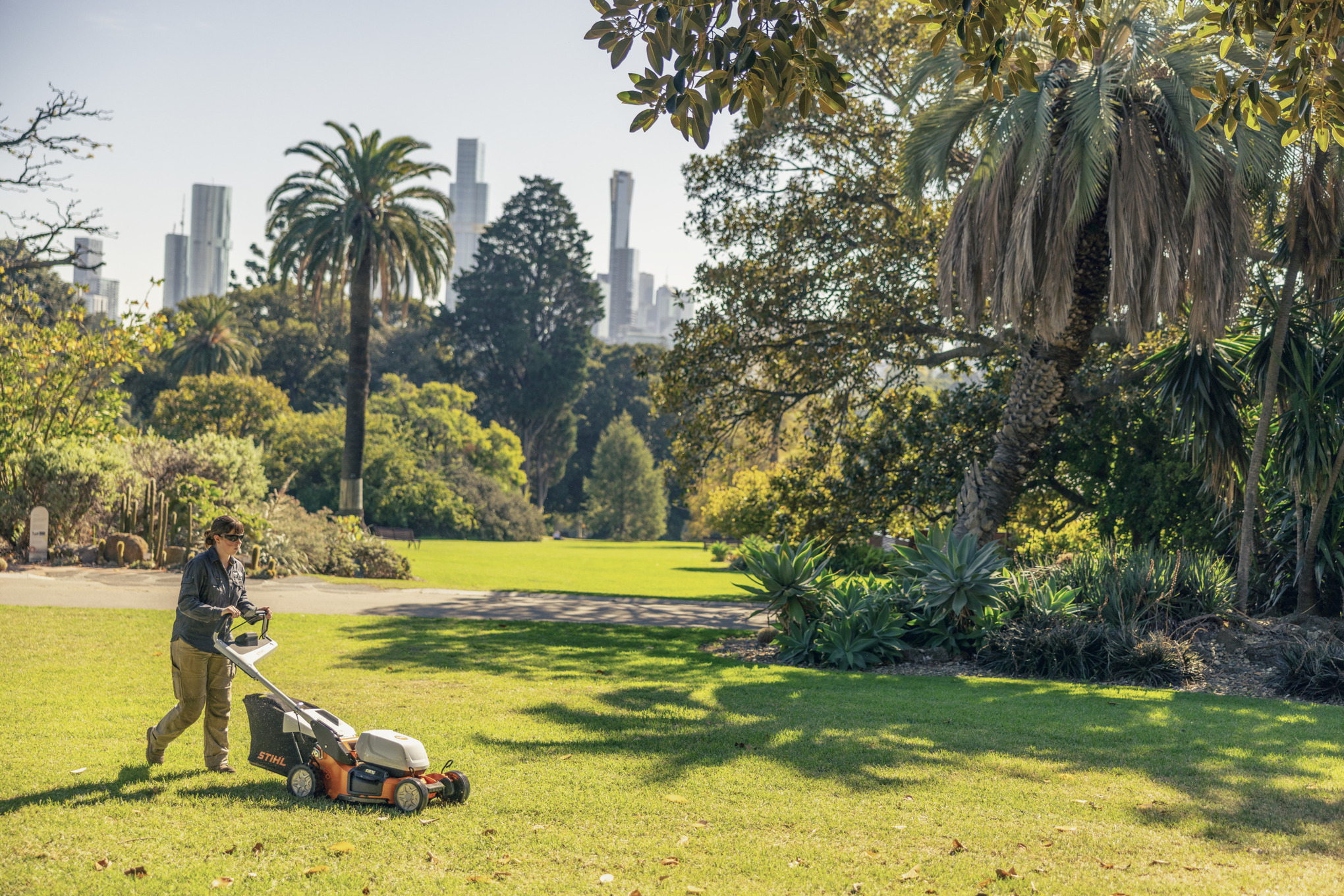 Victoria mäht den Rasen im sonnigen Botanischen Garten mit einem Akku-Rasenmäher RMA 756 V