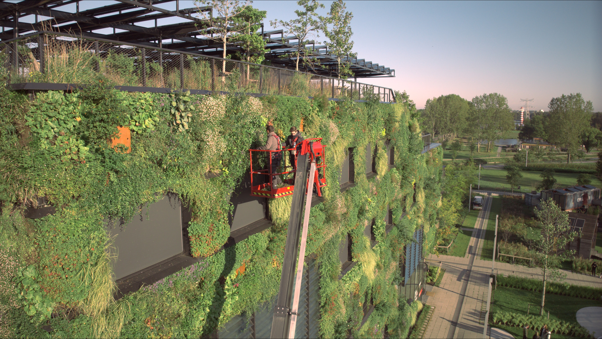 Zwei Arbeiter auf einer Hebebühne kümmern sich um die Gebäudebegrünung des Campus der Aeres Hogeschool