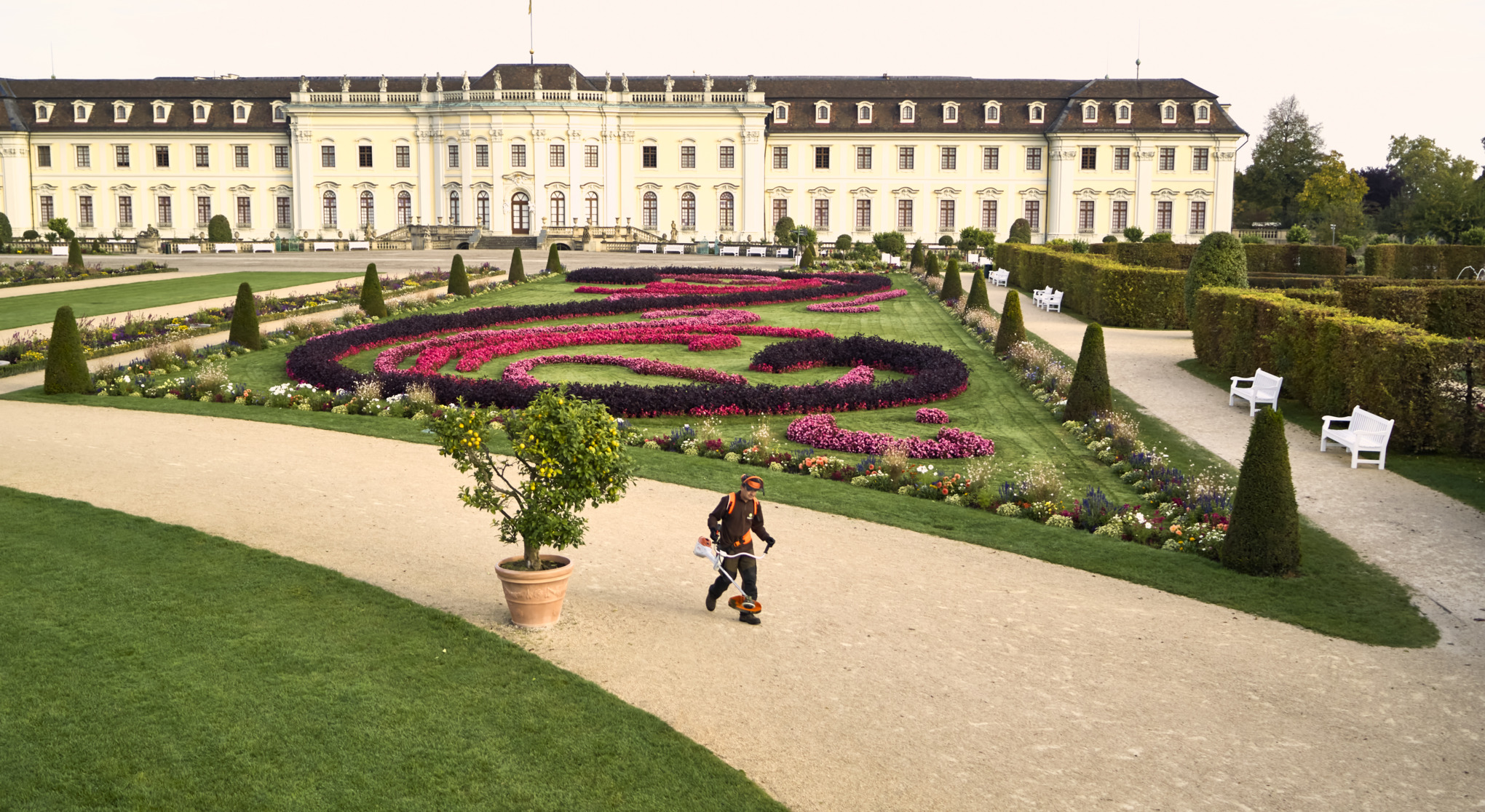 Man with the FSA 200 battery-powered brushcutter walks through the garden of the Residence Palace