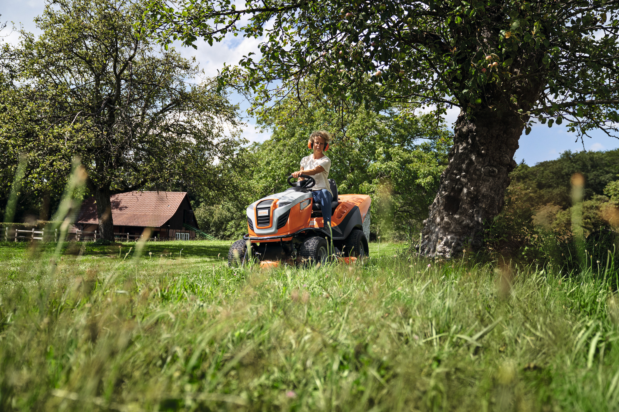 Mann steht mit STIHL Akku Heckenschere im Garten und ein Cashback 100€ Logo ist zu sehen.