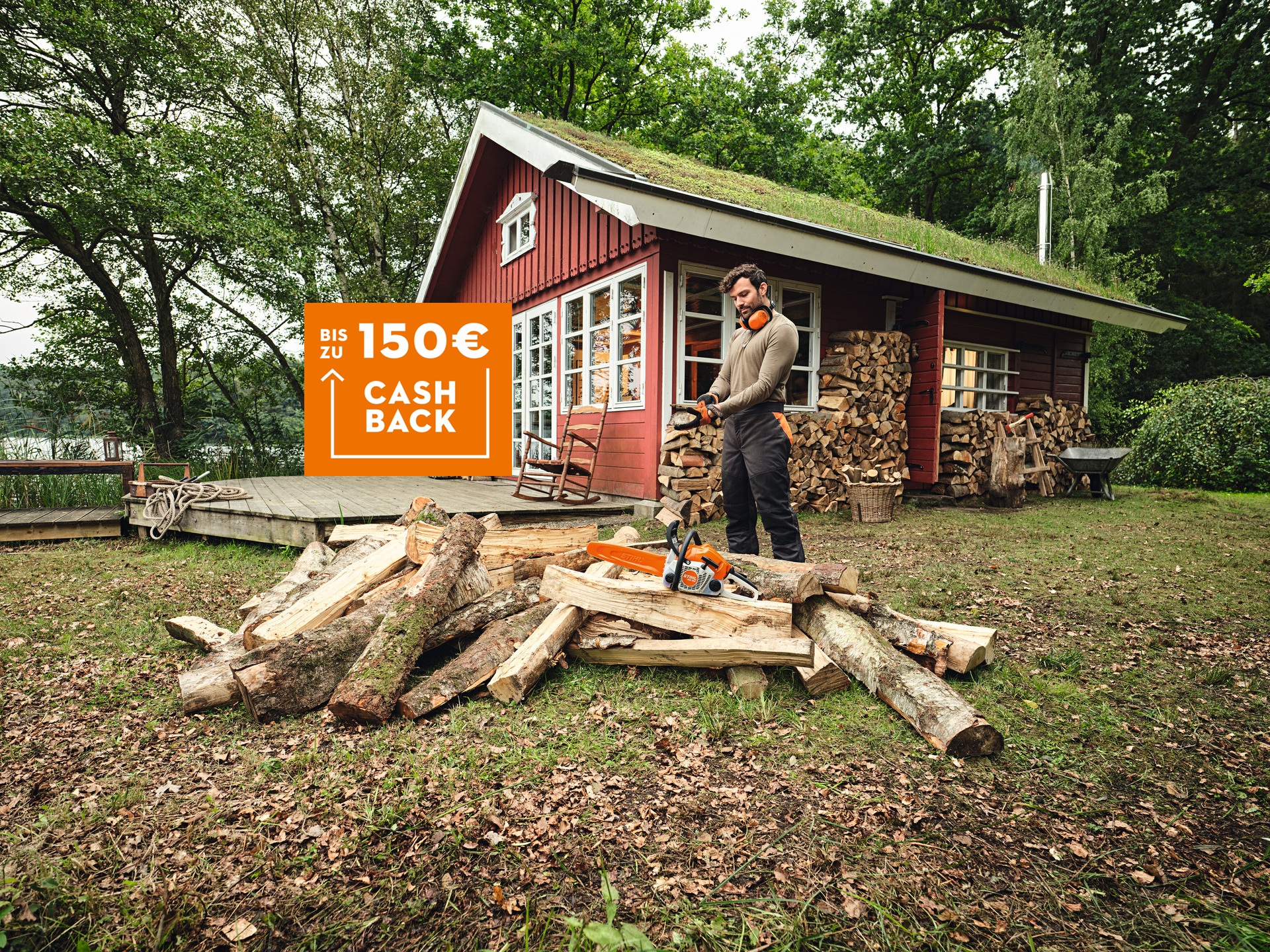 Person bereitet vor einer roten Holzhütte Brennholz mit einer STIHL MS 162 vor. Im Bild eingeblendet: „Bis zu 150 € Cashback“.