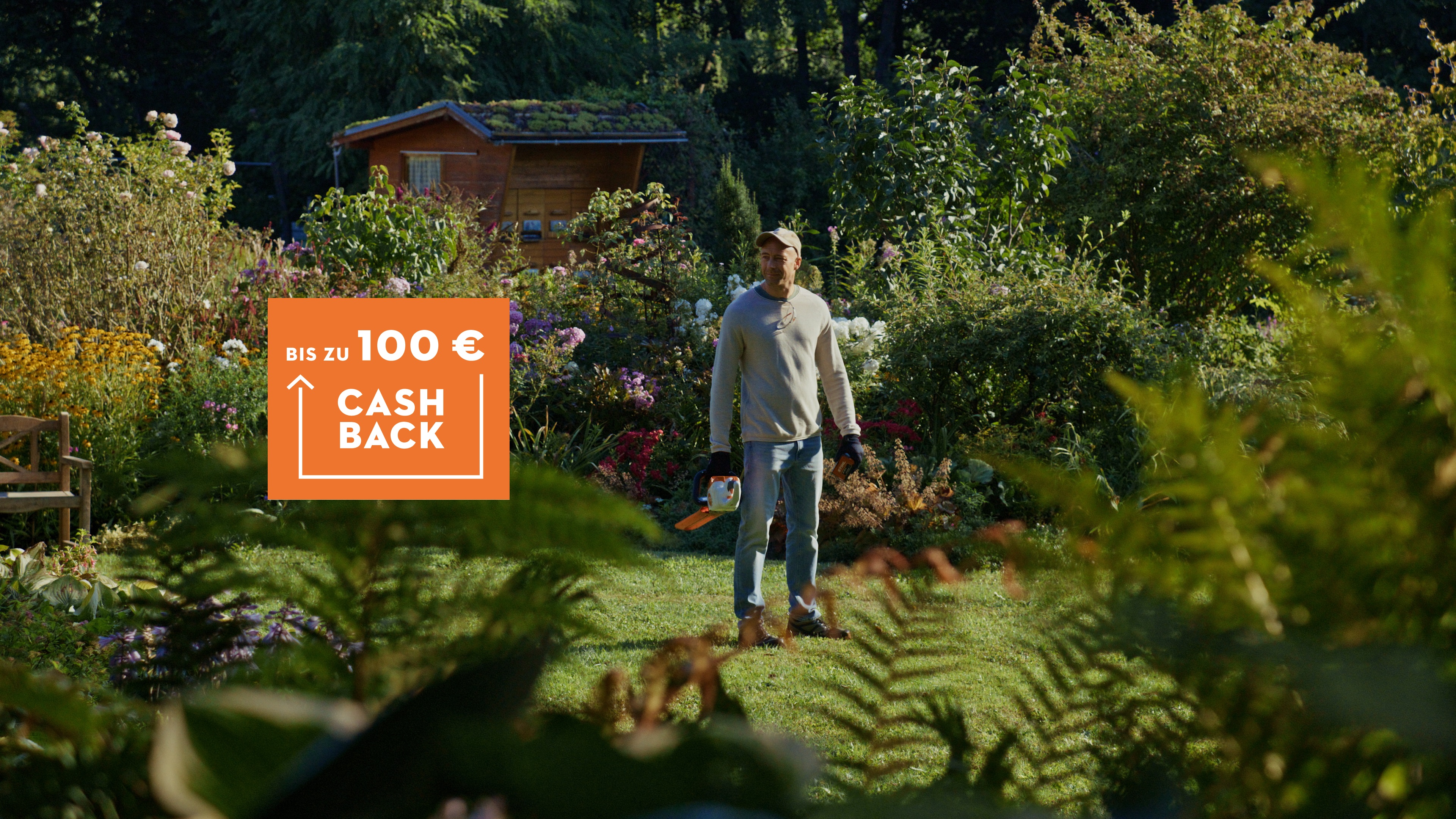 Mann steht mit STIHL Akku Heckenschere im Garten und ein Cashback 100€ Logo ist zu sehen.