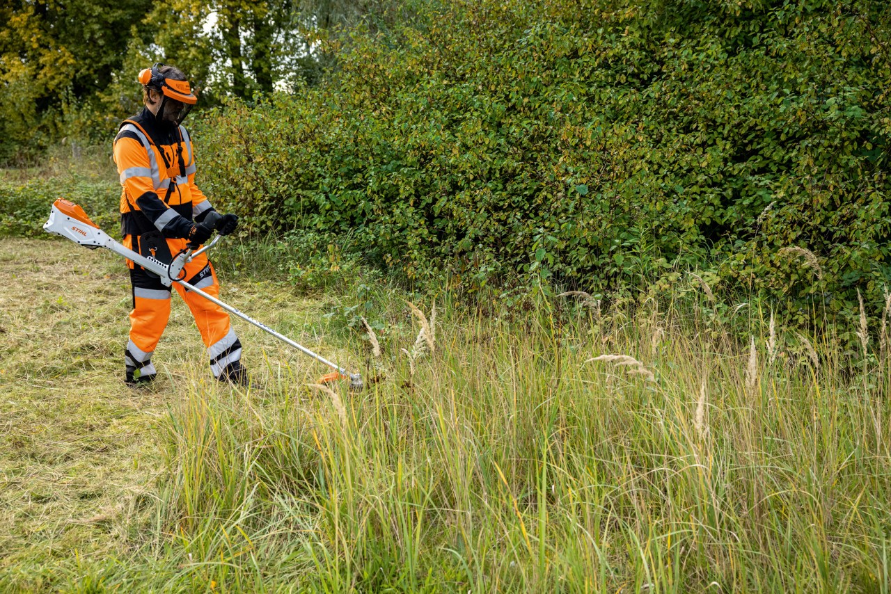 Mann in Schutzkleidung mäht hohes Gras mit STIHL Akku-Motorsense FSA 135