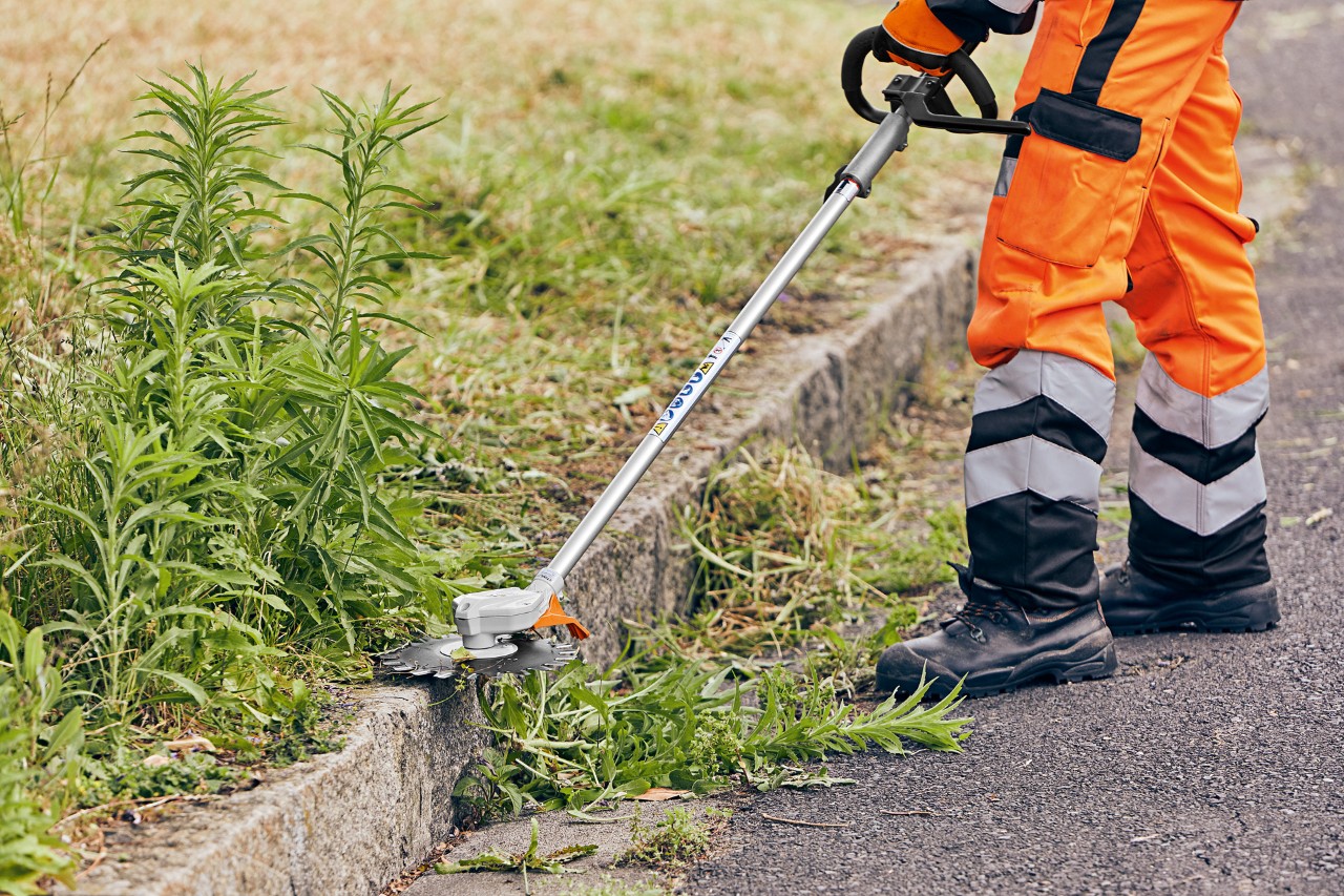 Unkraut an Bordsteinkante wird mit einem STIHL KombiGerät KMA 130 R gemäht