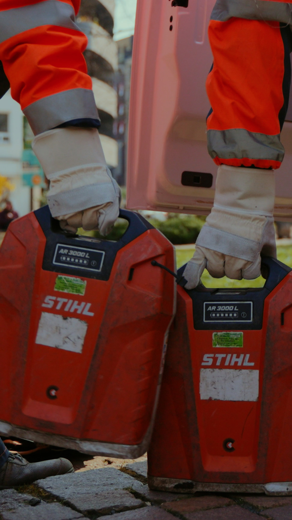 Professionelle Mitarbeiter der Stadtreinigung halten jeweils STIHL rückentragbare Akkus in der Hand