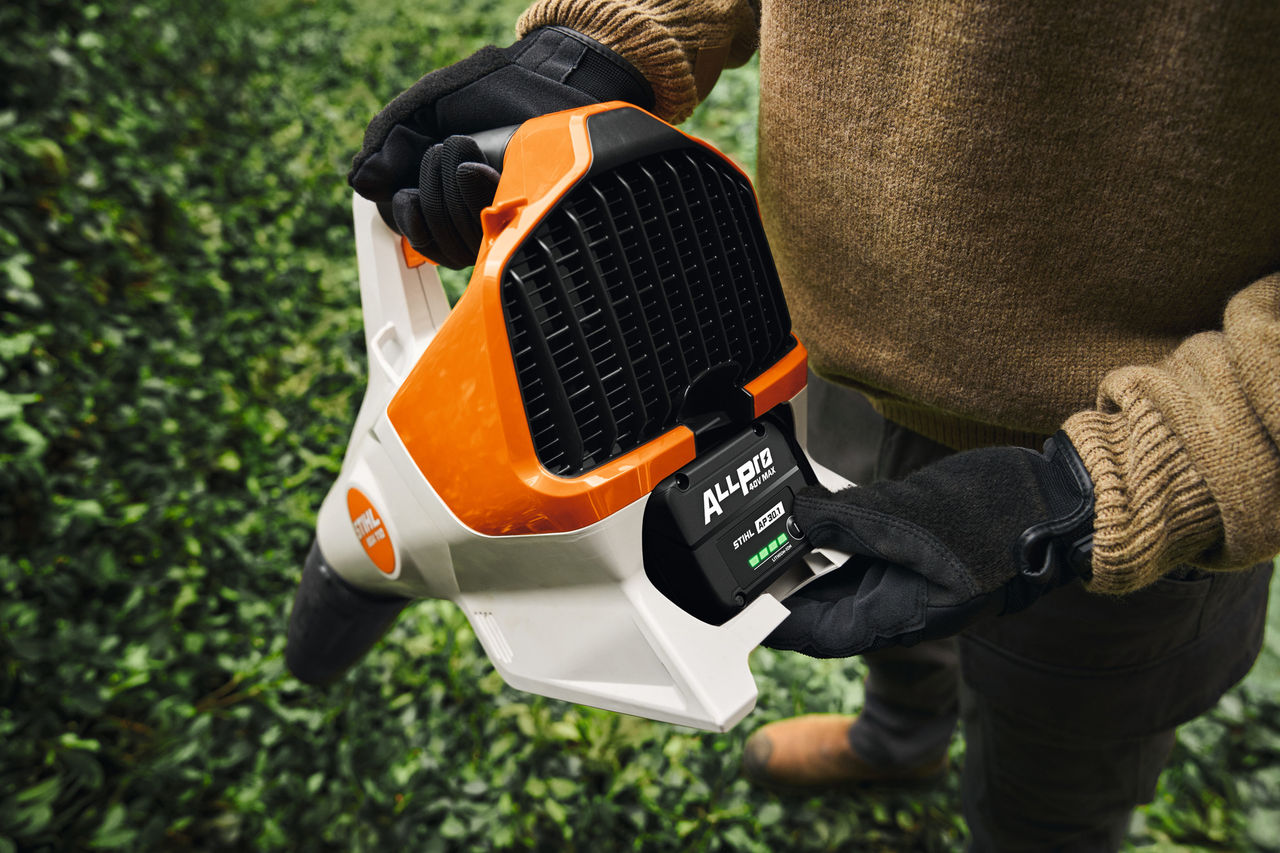 Ein Mann schaltet den Akku seines kabellosen Laubbläsers STIHL BGA 110 mit dem Akku STIHL AP 30 Evo 1 ALLPRO ein