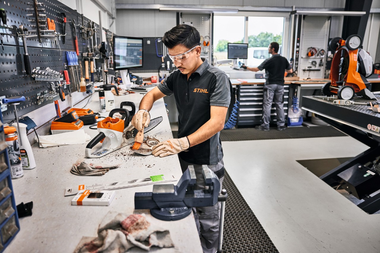 Mann in Werkstatt reinigt Kettenraddeckel einer STIHL Motorsäge