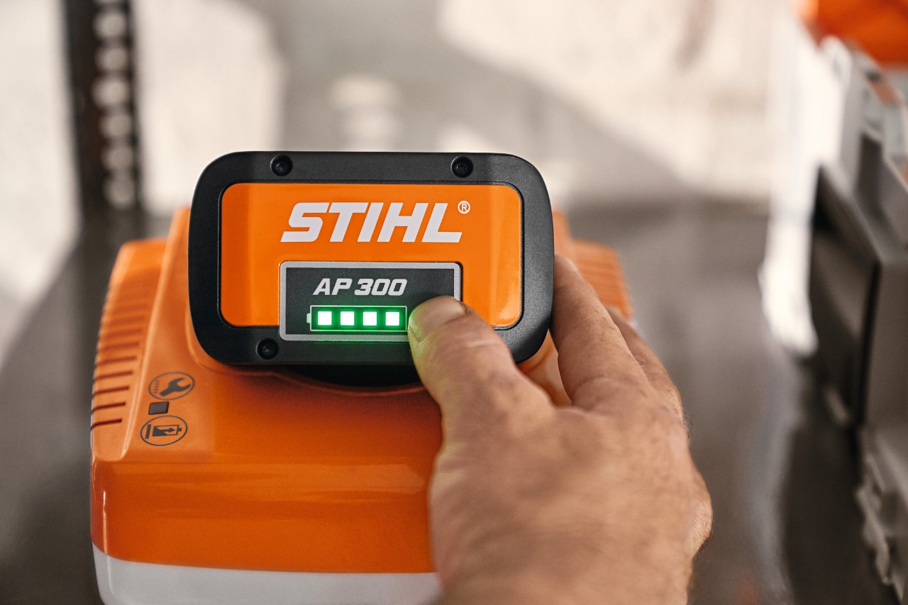 Ein Mann saugt in einer Garage mit einem STIHL Nass- und Trockensauger den Boden, neben ihm eine Werkbank und ein weißes Auto